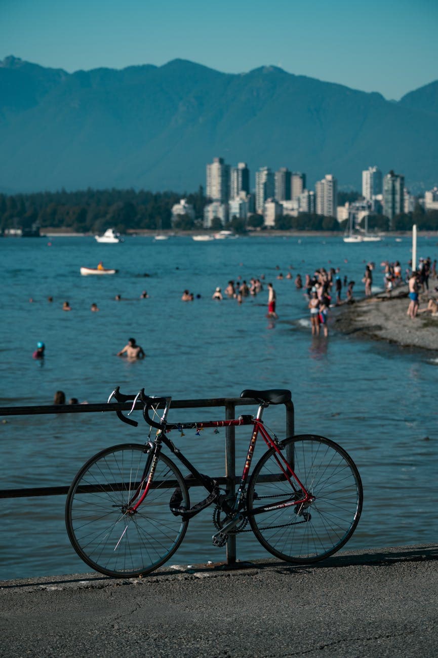 English Bay waterfront in Vancouver with swimmers, the West End skyline, and North Shore mountains in the background