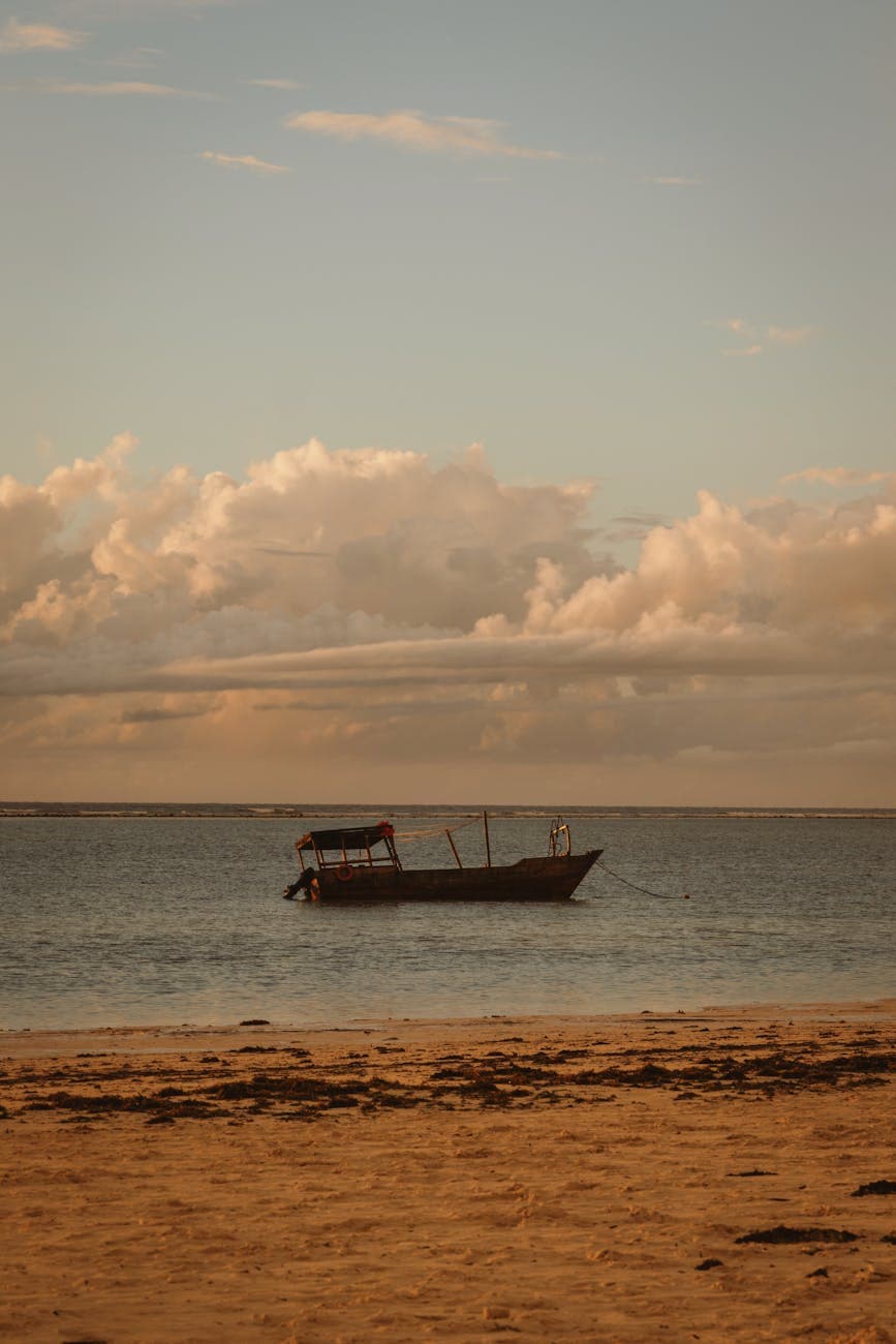 Traditional dhow boat on a Zanzibar beach at sunset with warm golden light over the Indian Ocean