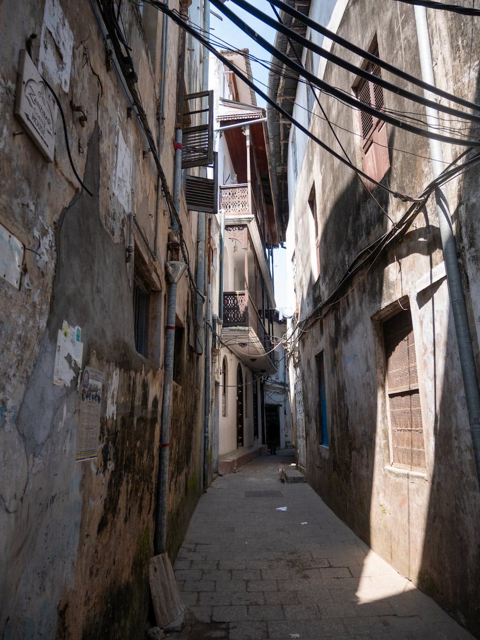 Narrow cobblestone alley in Stone Town, Zanzibar with aged stone facades and Swahili architecture