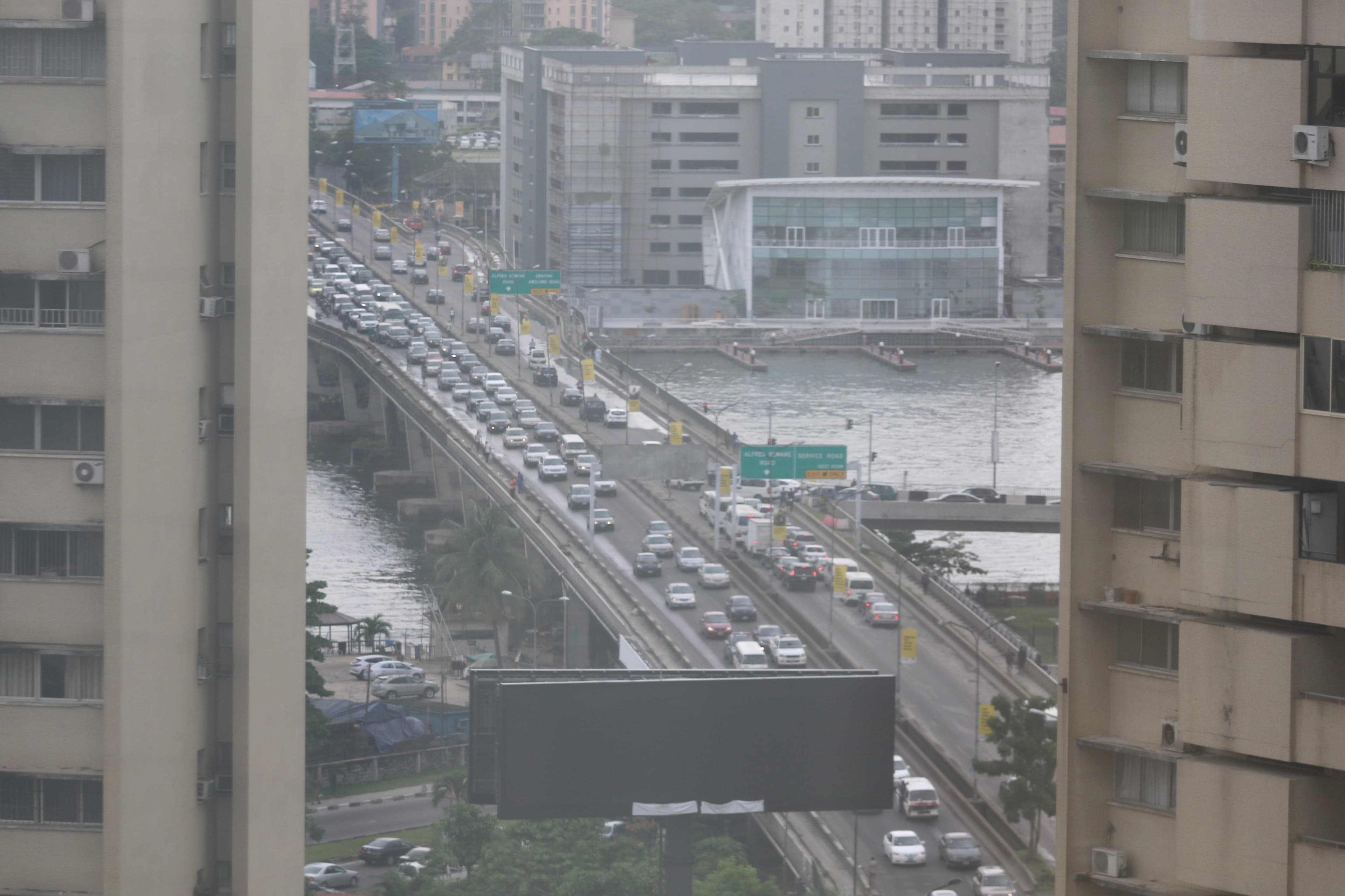 Heavy traffic on a Lagos roadway beside the lagoon